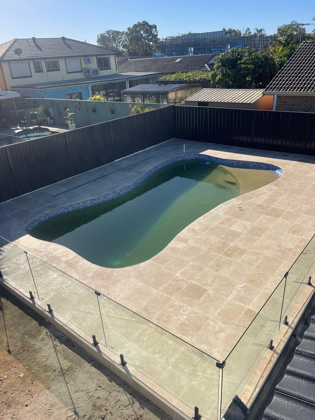 Completed pool with travertine surround and glass balustrade