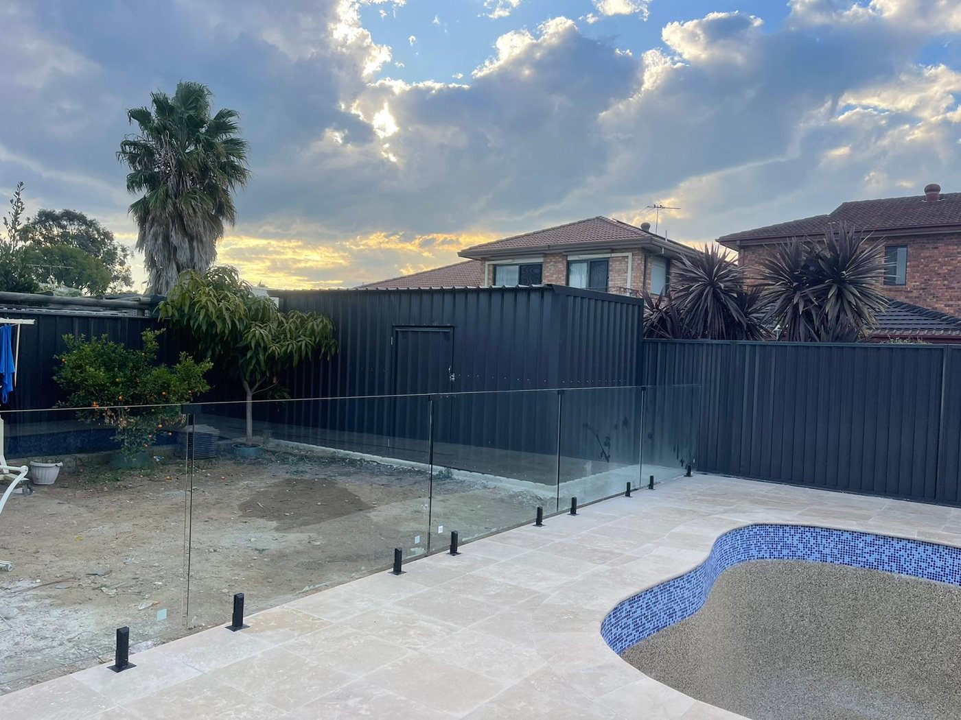 New pool with glass fencing and paving at sunset
