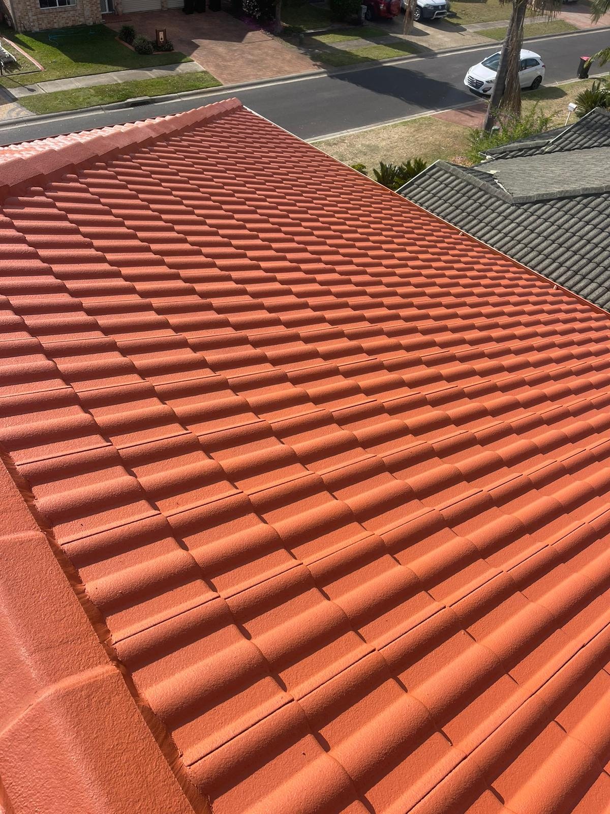 Restored terracotta roof with clean ridge and tile lines after re-pointing and coating