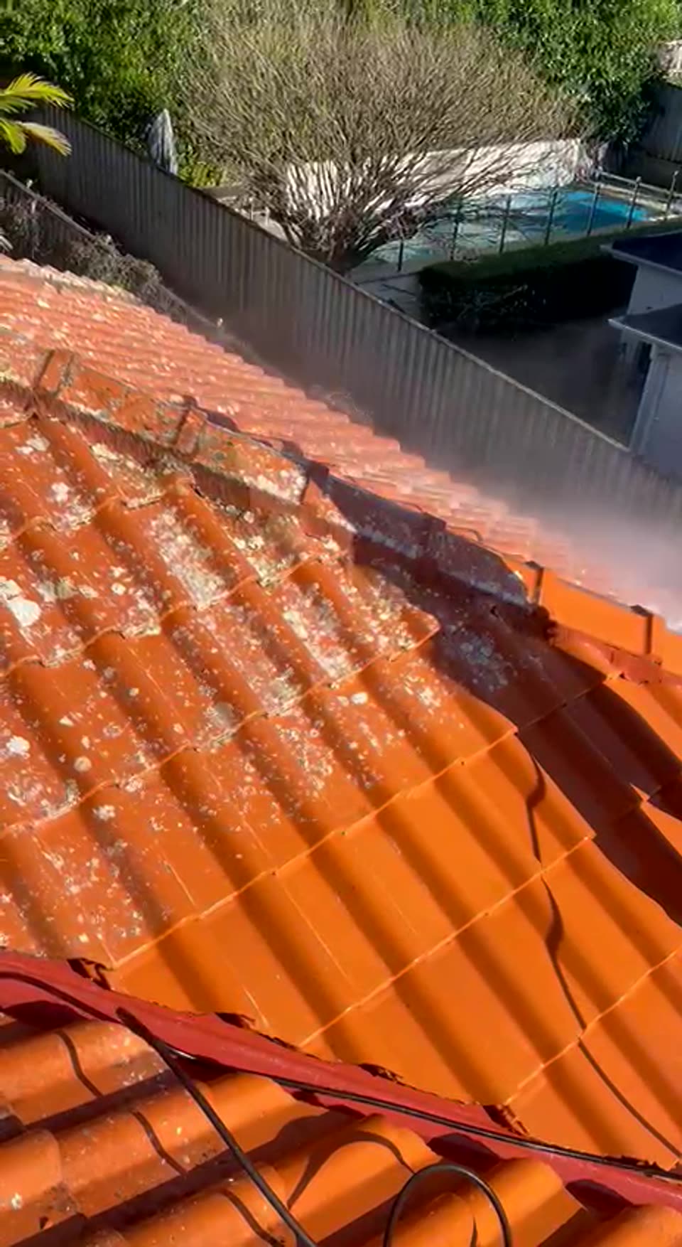 High pressure cleaning of a lichen-covered terracotta tile roof